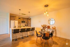 A modern kitchen with a central island, bar stools, and pendant lighting.