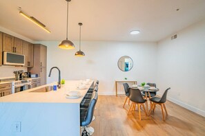 A modern kitchen with a central island, wooden cabinets, and pendant lighting. - Stadium-Adjacent | Pool, Balcony, Parking, Hot Tub (Glendale)