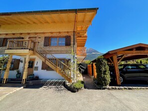 Ein Holzhaus mit Treppe, einem Balkon und einem Berg im Hintergrund.