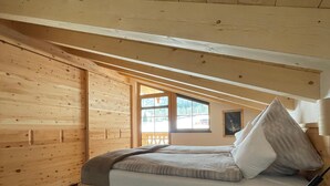 Un dormitorio de cabaña de madera con una cama, una ventana y piso de madera.