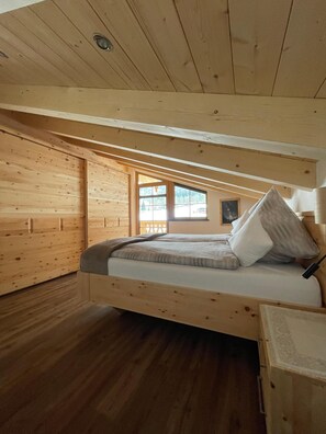 Ein Schlafzimmer einer Holzhütte mit einem Bett, einem Fenster und Holzboden.