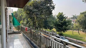 Un balcon doté d’une rambarde en métal donnant sur une route où se trouve une voiture blanche.