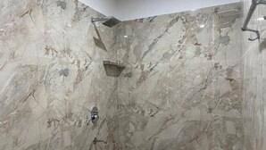 Une salle de bain avec des murs en marbre, une douche et un porte-serviettes.