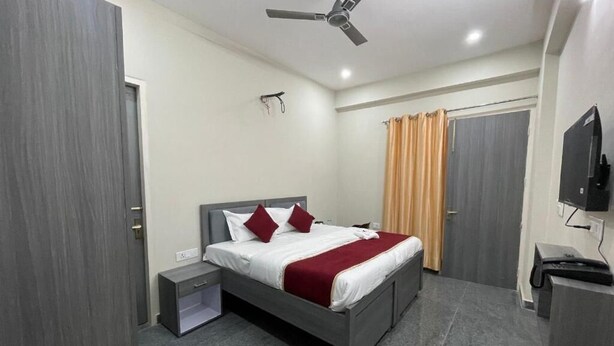 Une chambre d’hôtel équipée d’un lit, d’une table de chevet, d’un bureau, d’une télévision et d’un ventilateur de plafond.