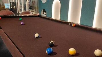 A pool table with balls and a wall with circular cutouts.