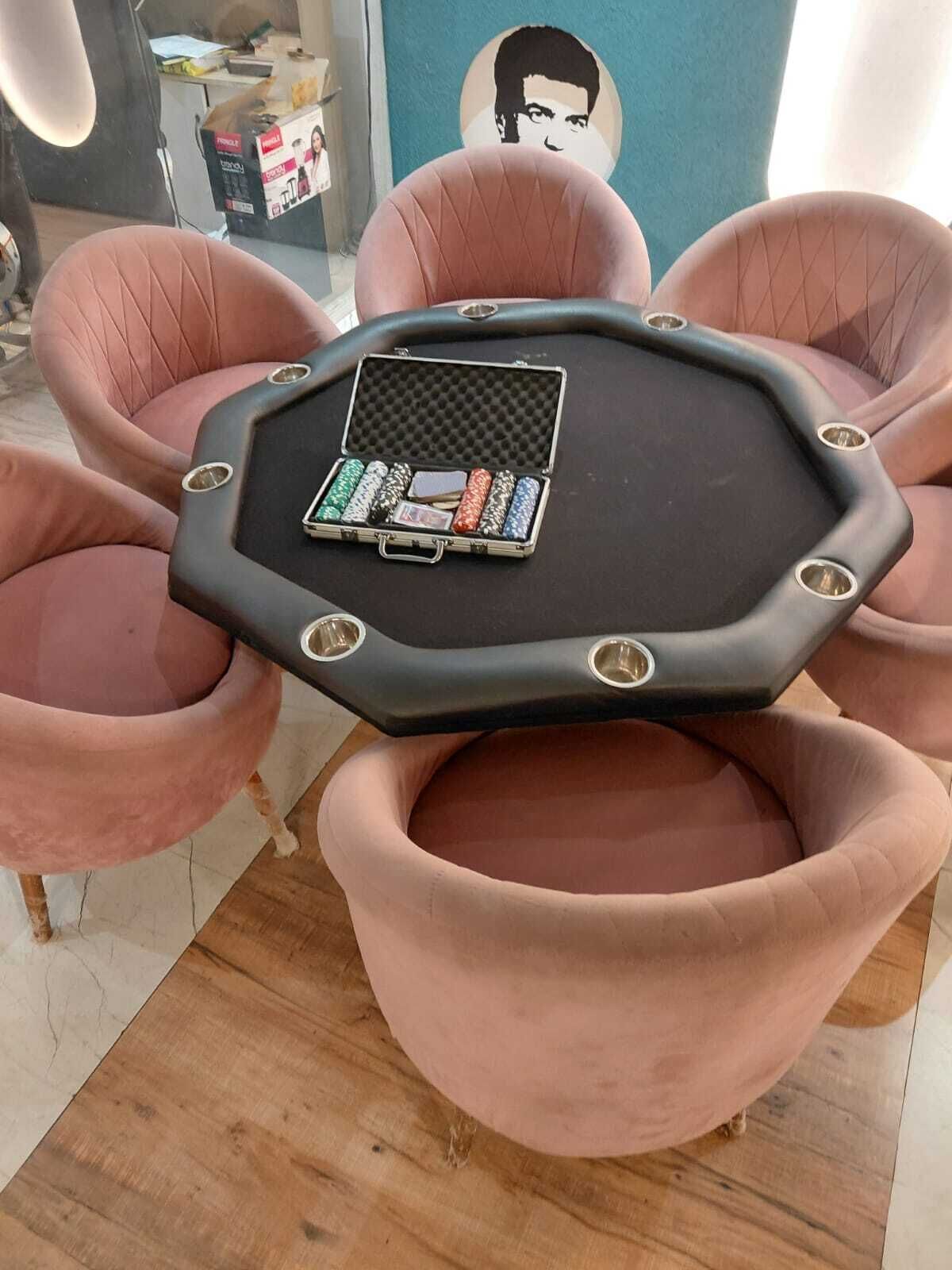 A round table with a black surface and a set of poker chips in a metal case.