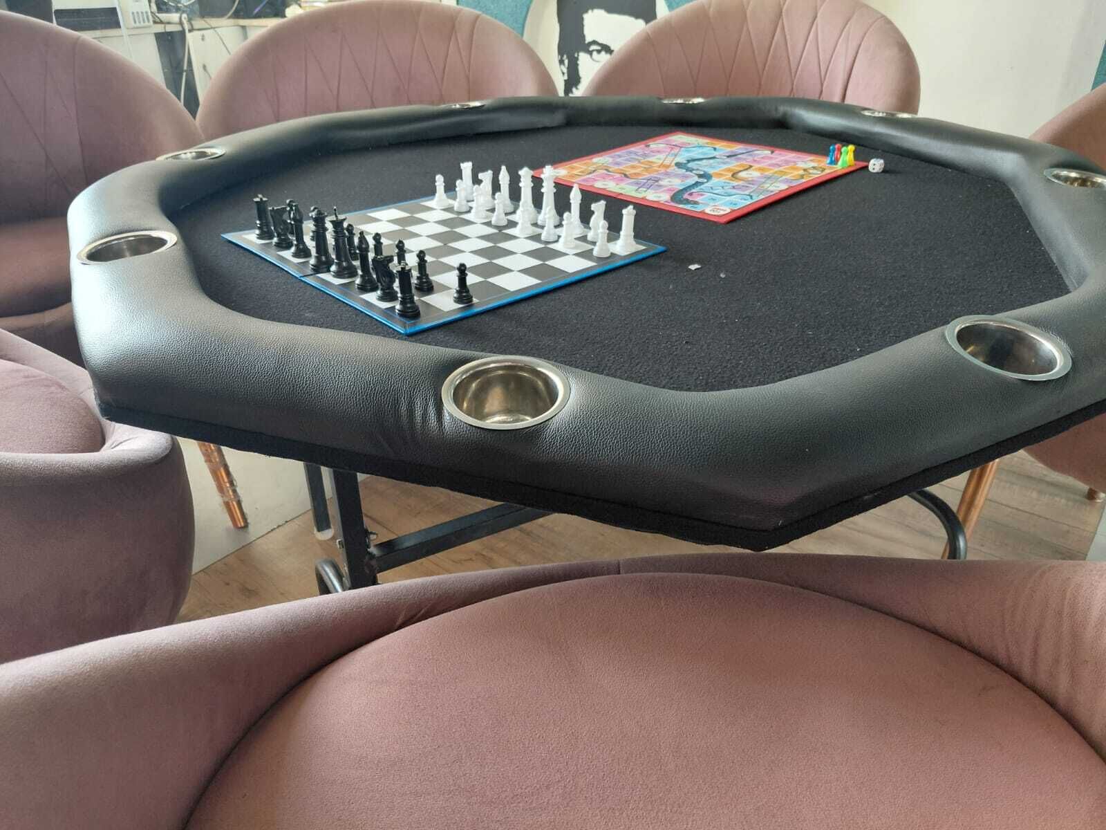 Ett bord med ett schackbräde och en pågående schackmatch, omgivet av stolar.