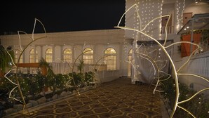 An outdoor courtyard with patterned flooring, decorative lighting, and a building with arched windows in the background. - Ravira Resort (Sitapur)