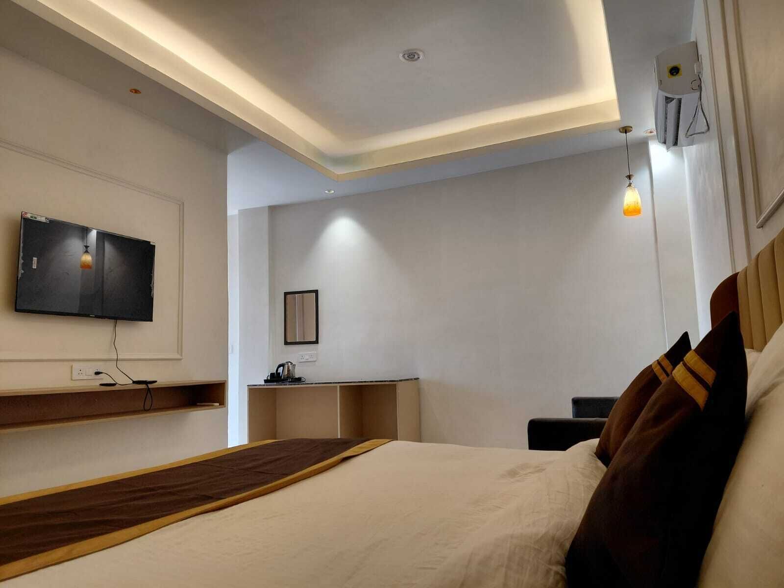 Une chambre d’hôtel moderne dotée d’un grand lit, d’un téléviseur à écran plat fixé au mur, d’un bureau et d’une table de chevet.