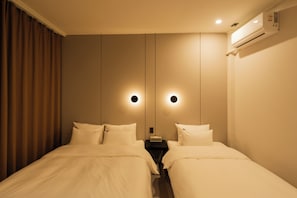 A hotel room with two beds, a nightstand, an air conditioning unit, and a mirror with wall-mounted lighting. - RESTIA STAY GANGNEUNG STATION (Gangneung)