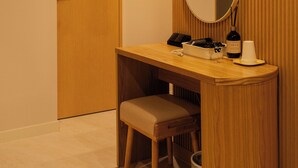 Une pièce comprenant une coiffeuse en bois, un banc, un miroir et une porte.