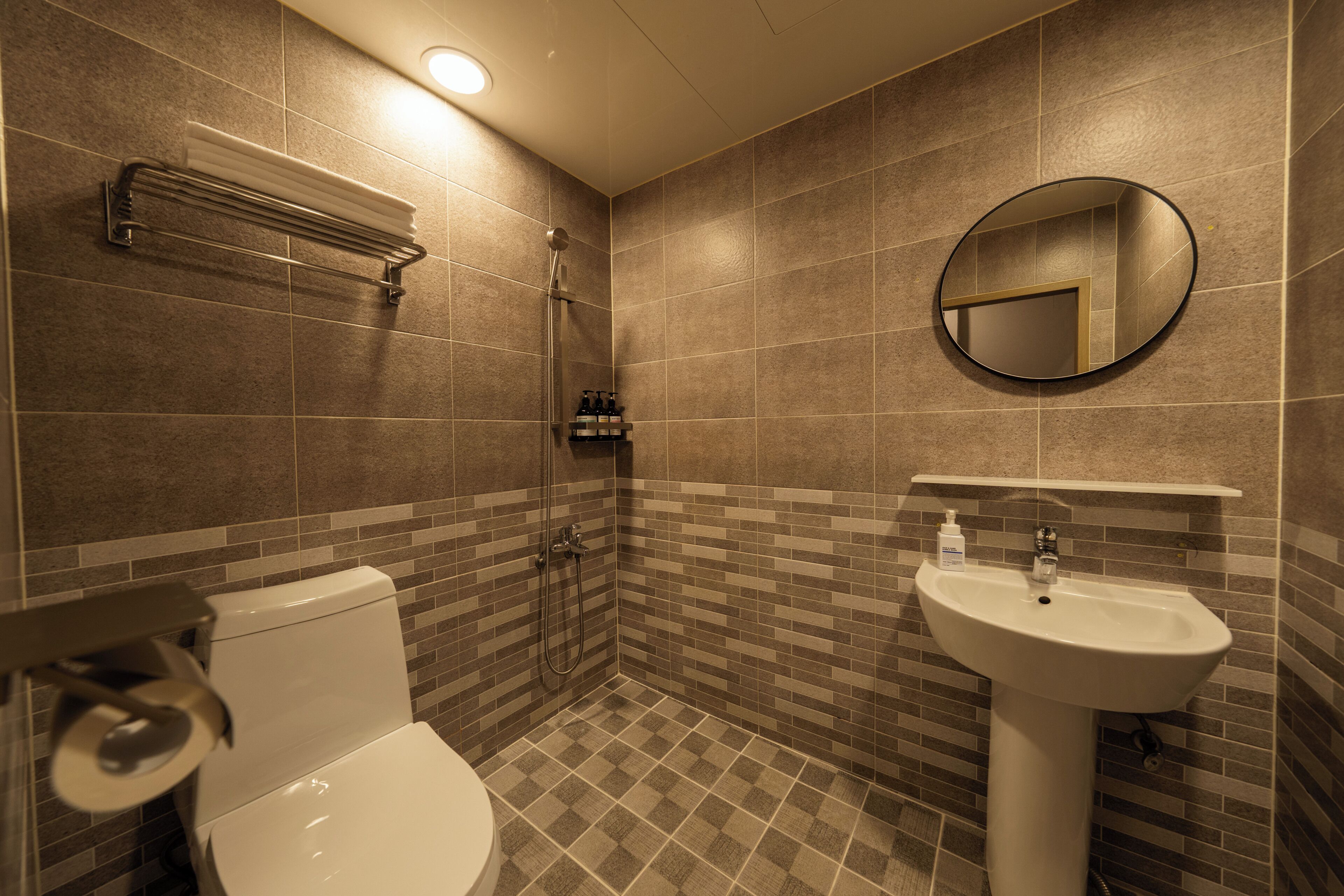 Ein Badezimmer mit Toilette, Waschbecken, Dusche und einem Spiegel an der Wand.