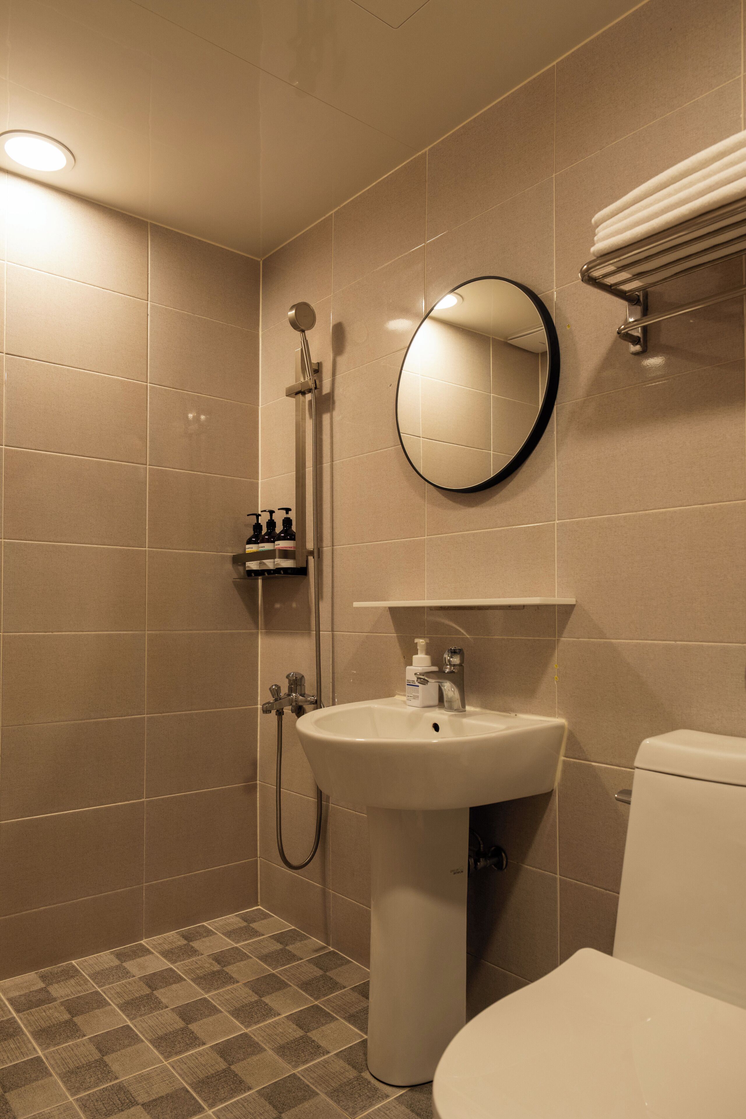 A bathroom with a shower, sink, toilet, and a mirror.