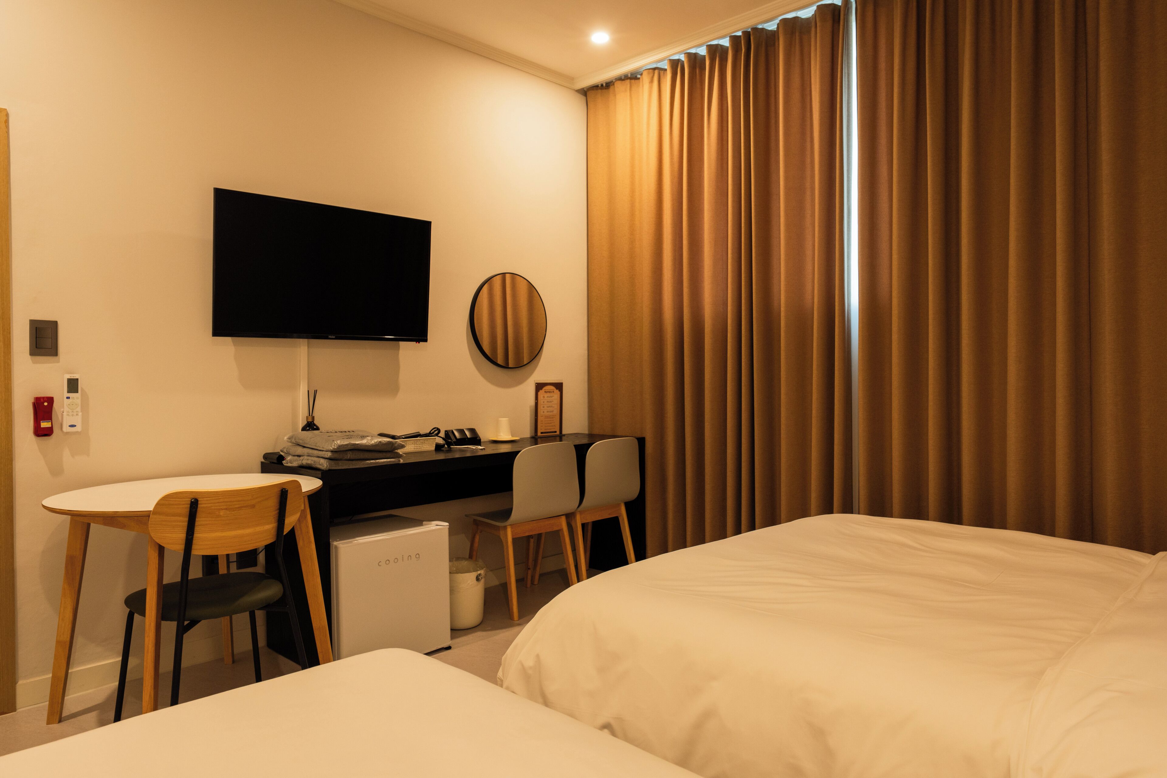 Una habitación de hotel con cama, escritorio con computadora, silla, televisor y ventana con cortinas.