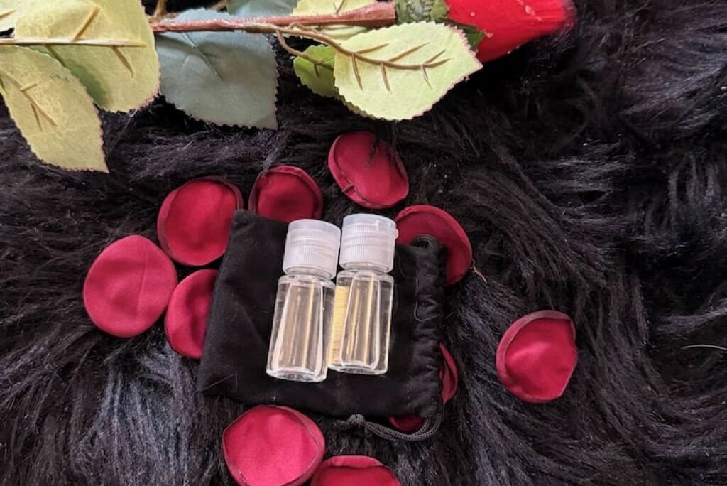 A black furry surface with scattered red petals and two clear bottles in a black pouch.