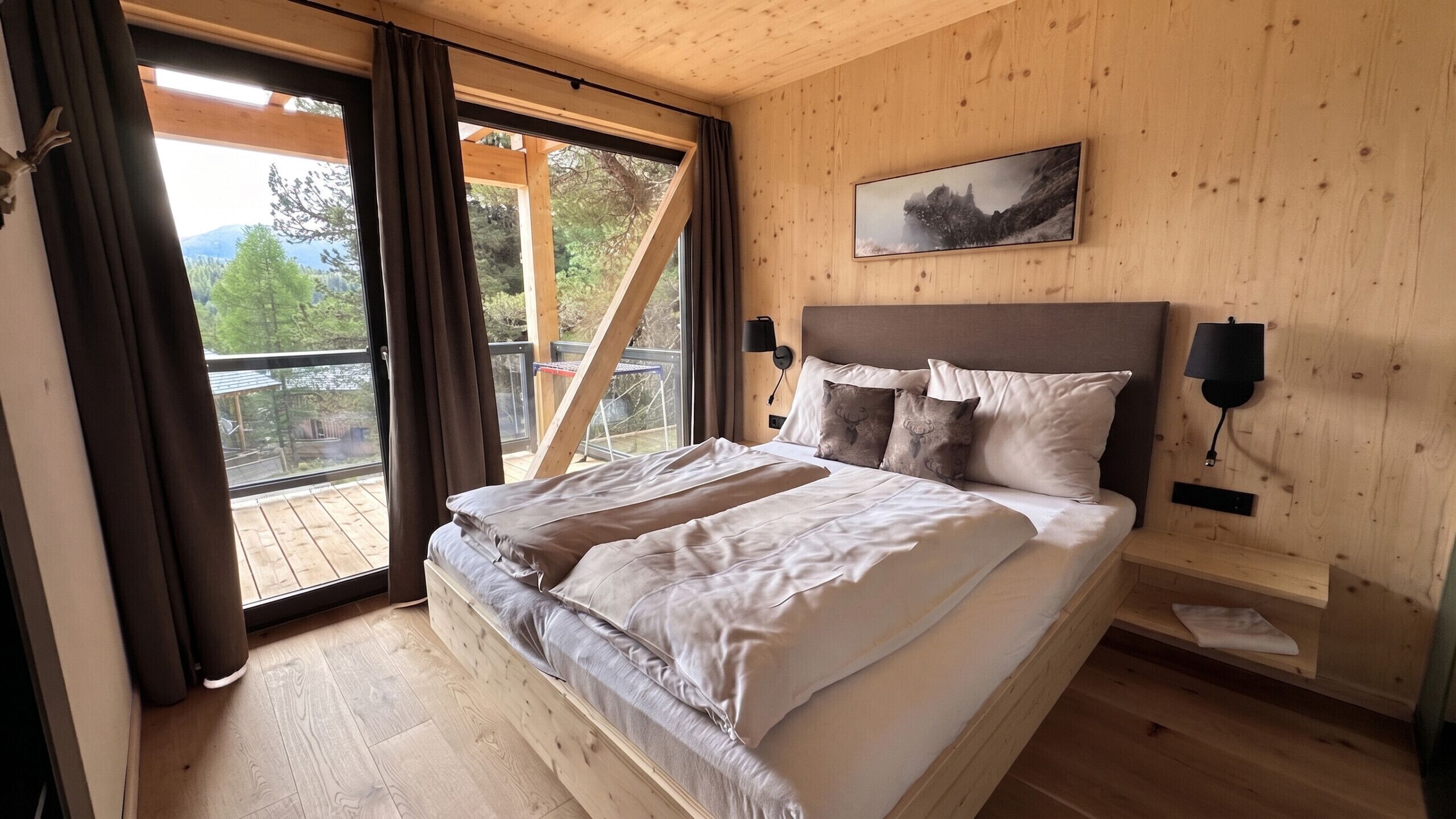 Een slaapkamer met een bed, uitzicht op het landschap en een schilderij aan de muur.
