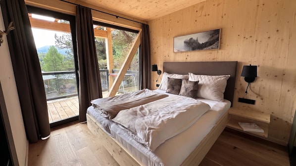 A bedroom with a bed, a view of the outdoors, and a painting on the wall. - Superior Chalet # 51 with Sauna & Hot Tub (Turrach)