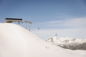 Ein mit Schnee bedeckter Berg mit einer Seilbahn und einem Gebäude auf der linken Seite.
