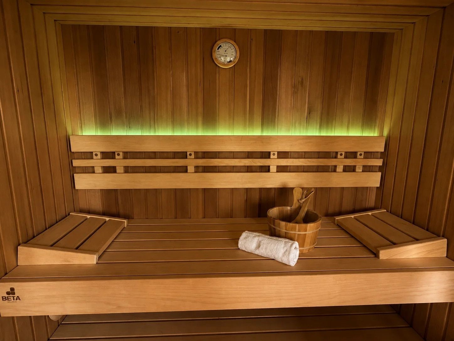 A wooden sauna with a bench, a wooden bucket, and a towel.