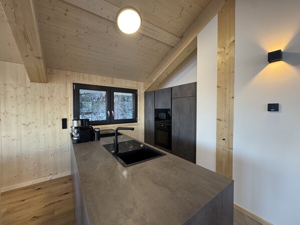 Eine moderne Küche mit Holzwänden, einem großen Fenster und integrierten Geräten.