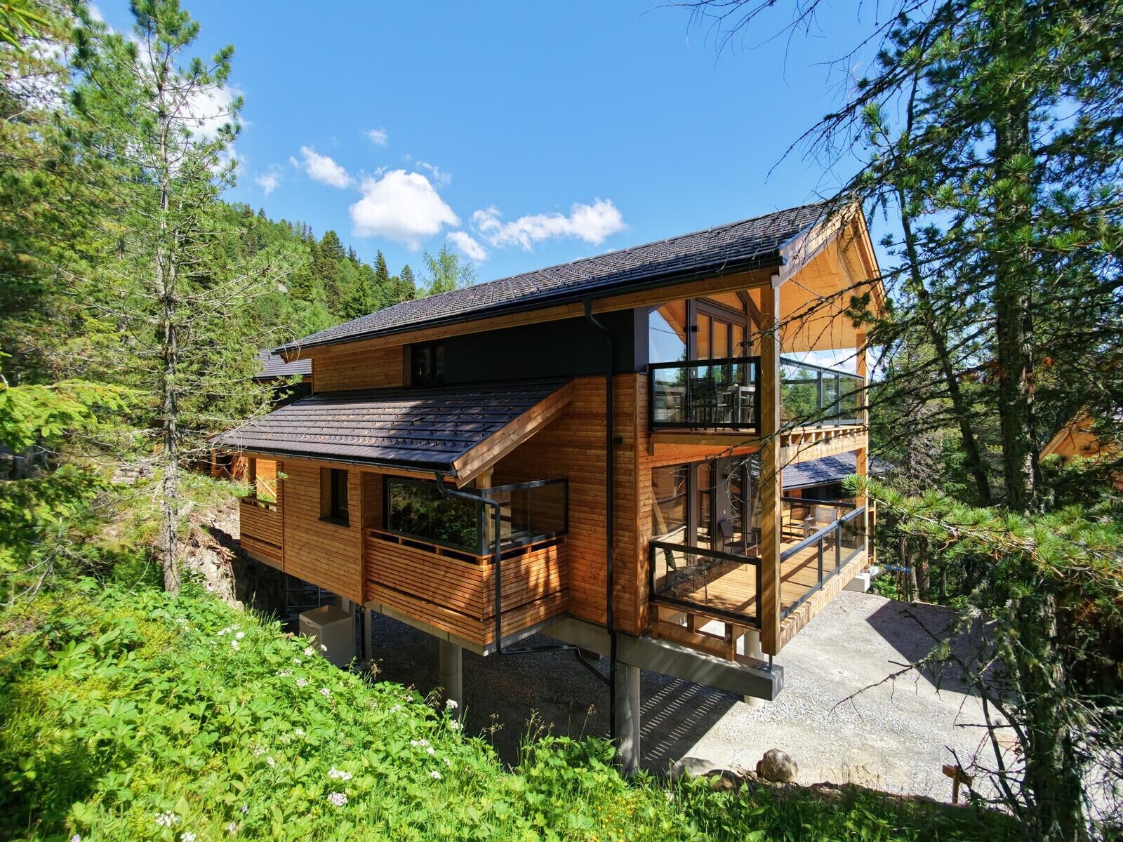 Une cabane en bois dotée d’un balcon, entourée de verdure et d’arbres.