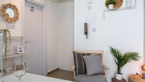 A modern room with a wooden chair, a small table with a glass, and a shelf with decorative items. - Orchid Cozy Studio & Balcony in Larnaca (Larnaca)