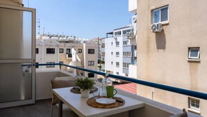 A balcony with a table, a potted plant, and a view of neighboring buildings. - Orchid Cozy Studio & Balcony in Larnaca (Larnaca)