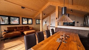 Ein Holzinnenraum mit Esstisch, Sofa und Sesseln.