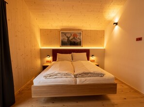 Une pièce avec un lit, des murs en bois, un tableau et des lampes fixées au mur.