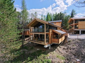 Une cabane en bois à deux étages, dotée d’un balcon et entourée d’arbres.