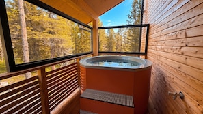 Un bain à remous dans un chalet en bois avec vue sur une forêt.