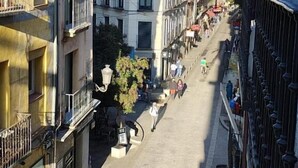Eine schmale Straße gesäumt von mehrstöckigen Gebäuden, einige mit Balkonen und andere mit Geschäften im Erdgeschoss.