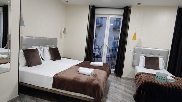Ein Hotelzimmer mit zwei Betten, einem großen Spiegel, einem Deckenventilator und Blick auf den Balkon.