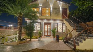A two-story house with a stone facade, a wooden staircase, and a tiled entrance area. - Manovan Resort by Eastlynn Experiences, Jim Corbett (Kaladhungi)