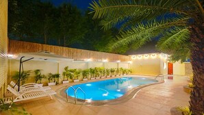 A swimming pool with a tiled deck, surrounded by lounge chairs and potted plants. - Manovan Resort by Eastlynn Experiences, Jim Corbett (Kaladhungi)
