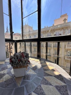 A corner room with a large window, a tiled floor, and a flower arrangement on a table. - Hostal Arenal Madrid (Madrid)
