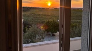 Zonsondergang boven een veld, te zien vanaf een balkon.