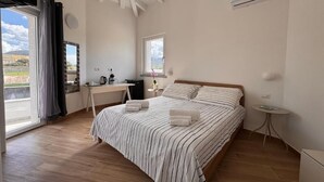 Een slaapkamer met een groot bed, een bureau en een raam.