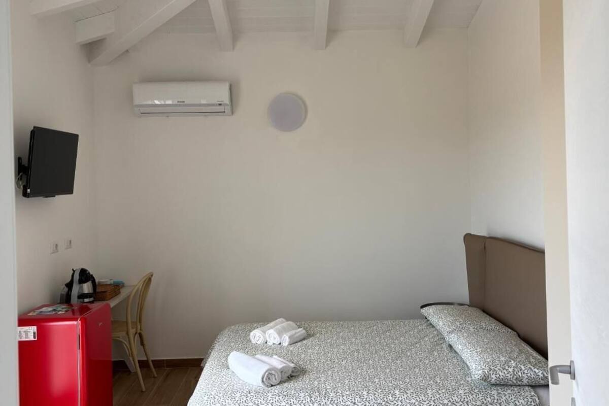 Un dormitorio con una cama, un escritorio, una silla, aire acondicionado y un televisor.