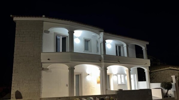 A multi-story building with a white facade and arched windows. - Domo IL Tramonto Giba (Giba)