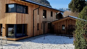 Eine Holzhütte mit großen Fenstern und verschneitem Gelände.