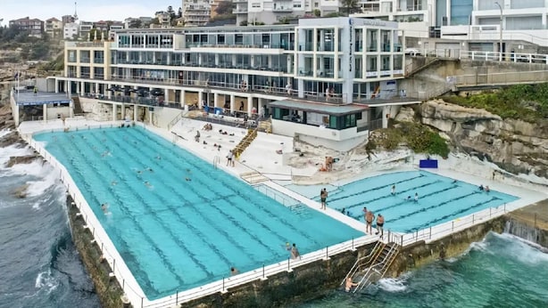 A coastal hotel with multiple swimming pools, a rocky shoreline, and a modern building with balconies. - Bondi Beachside Escape - Surf & Vibe (Bondi Beach)
