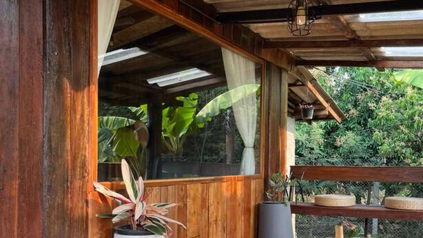 A wooden deck with a table and chairs, surrounded by potted plants and a view of greenery. - Boutique Cabin · Peaceful Mountain View (Mueang Ngai)