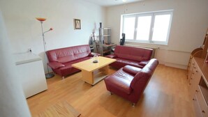 A living room with a red sofa set, a wooden coffee table, a floor lamp, and a radiator.