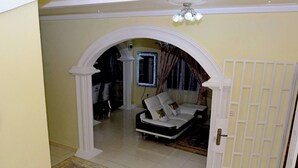 Un salon avec un canapé blanc, un lustre et un miroir décoratif.