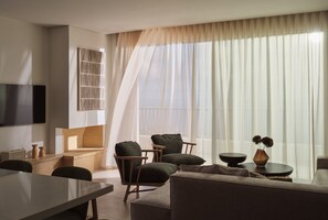 A modern living room with a flat-screen TV mounted on the wall, a sofa, two armchairs, a coffee table, and a dining area with a table and chairs. - Eliterra Villa I, Timeless Serenity & Heated Pool (VPW4+V62 Elation, Greece)