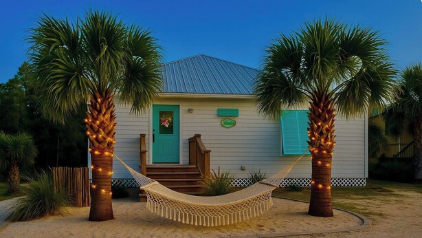 A house with a hammock between two palm trees, a front door, and a small porch. - 7001 Rookery 3 pools pet friendly Gulf Shores (Gulf Shores)