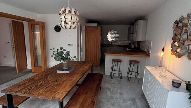 Een moderne keuken met een houten eettafel, stoelen en een wit aanrecht.