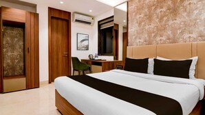 Ein Hotelzimmer mit einem großen Bett, einem Schreibtisch mit Stuhl, einem Kleiderschrank und einem Spiegel.