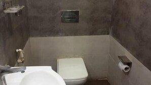 Ein kleines Badezimmer mit einem weißen Waschbecken, einer Toilette und einem Handtuchhalter.